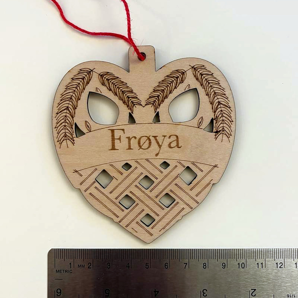 Woven heart name ornament photographed beside a metal ruler to show its size