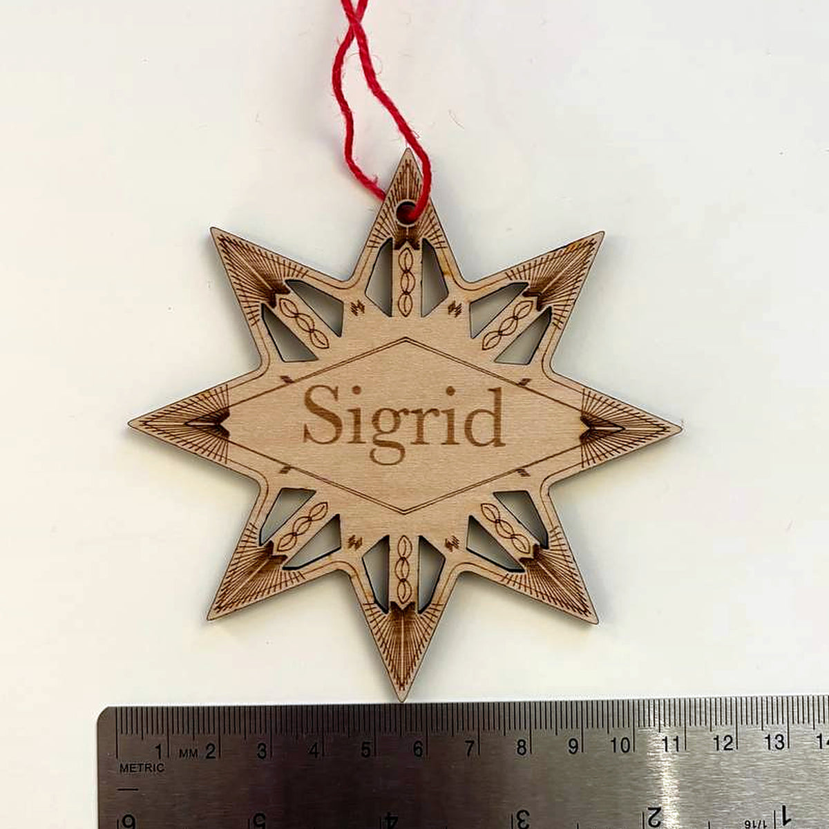 Winter star name ornament photographed above a metal ruler to show its size