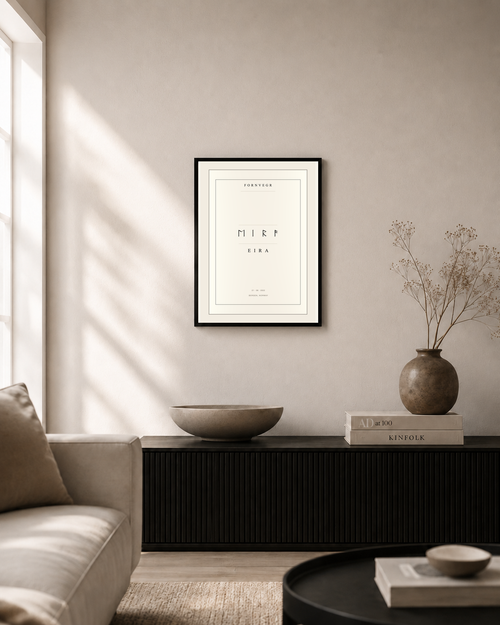 Elder Futhark name print in a black frame on a sunlit living room wall above a low black sideboard