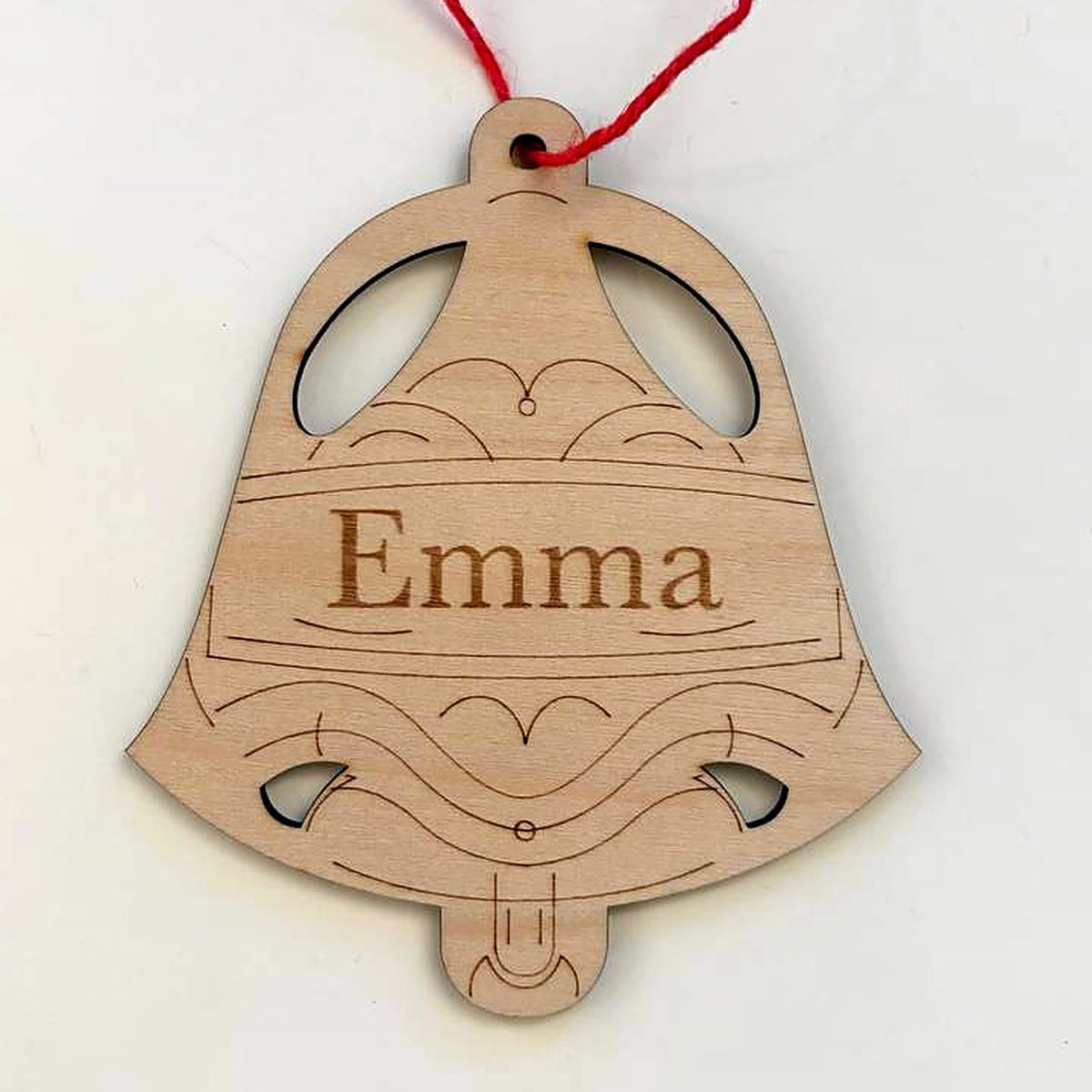 Winter bell Christmas ornament in laser-cut birch wood, engraved with the sample name Emma, hanging from a red cord