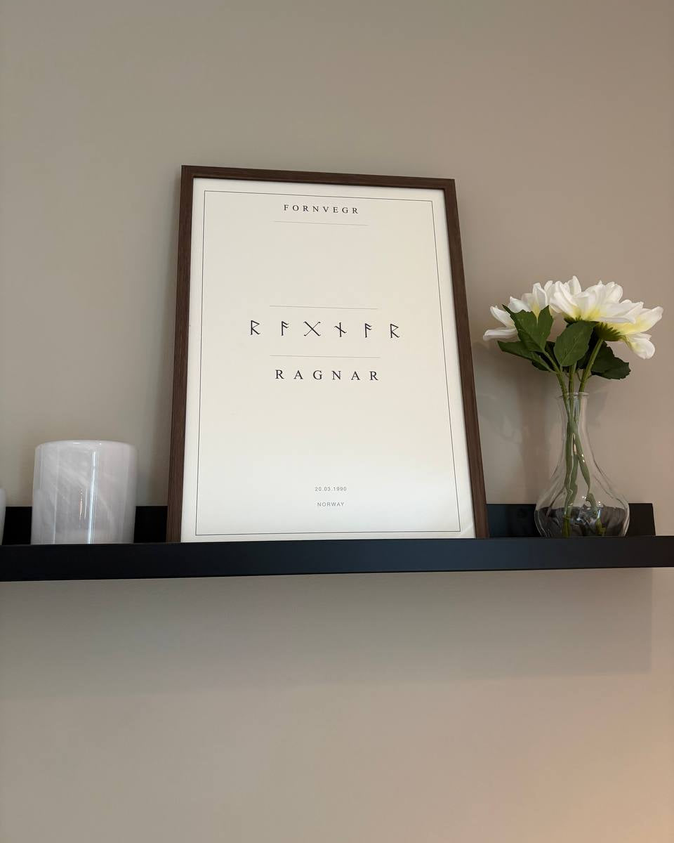 Full framed Elder Futhark Name Print above a shelf with a candle and vase for scale.